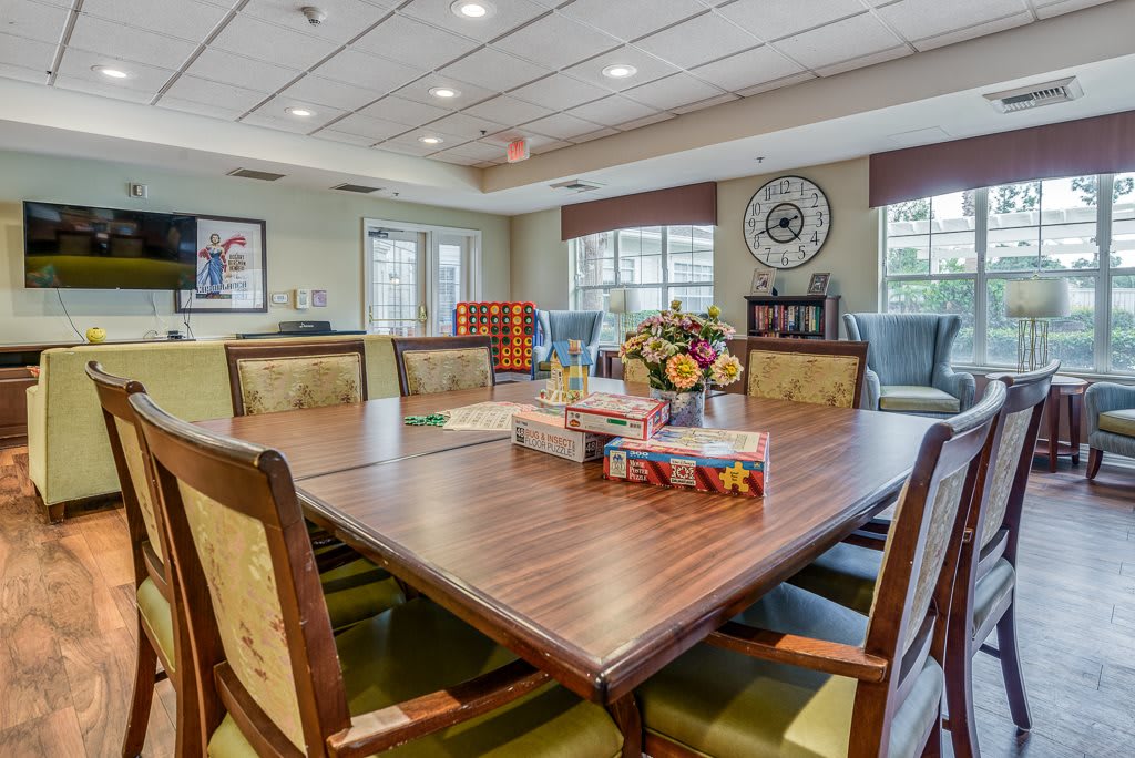 A well-lit conference room with a large wooden meeting table, surrounded by chairs and decorated with flowers.