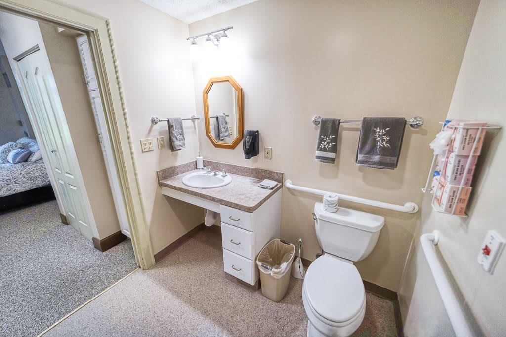 A clean and neatly organized bathroom with a sink, mirror, and toilet.