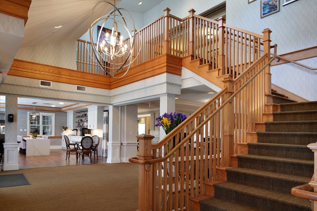 A spacious lobby with a wooden staircase and modern chandelier.