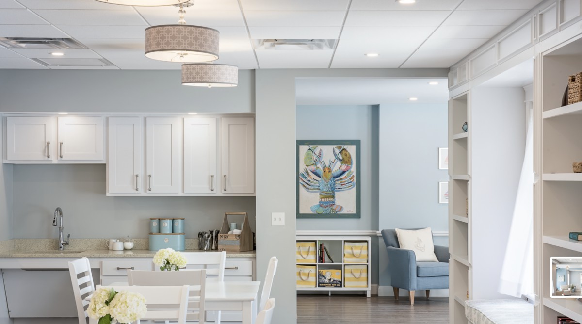 A modern interior featuring a kitchen with white cabinets and a cozy living area with comfortable seating and artwork.