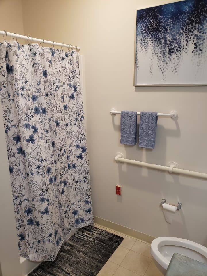 A neatly organized bathroom with a patterned shower curtain and matching towels.