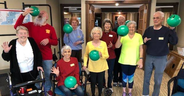 A group of seniors smiling and holding exercise balls in an indoor setting.