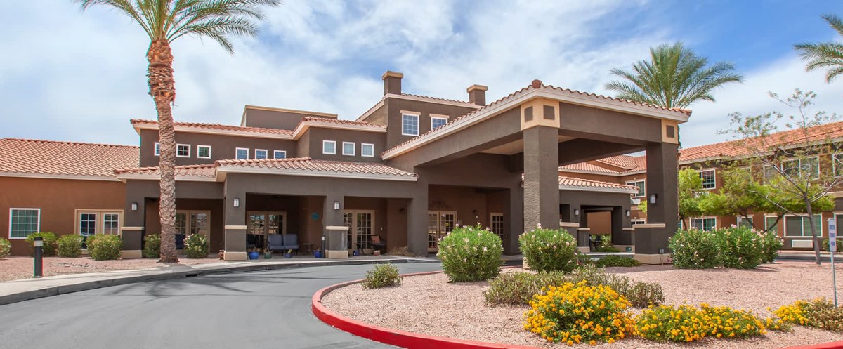 A hotel building with an entrance surrounded by landscaped gardens under a cloudy sky.