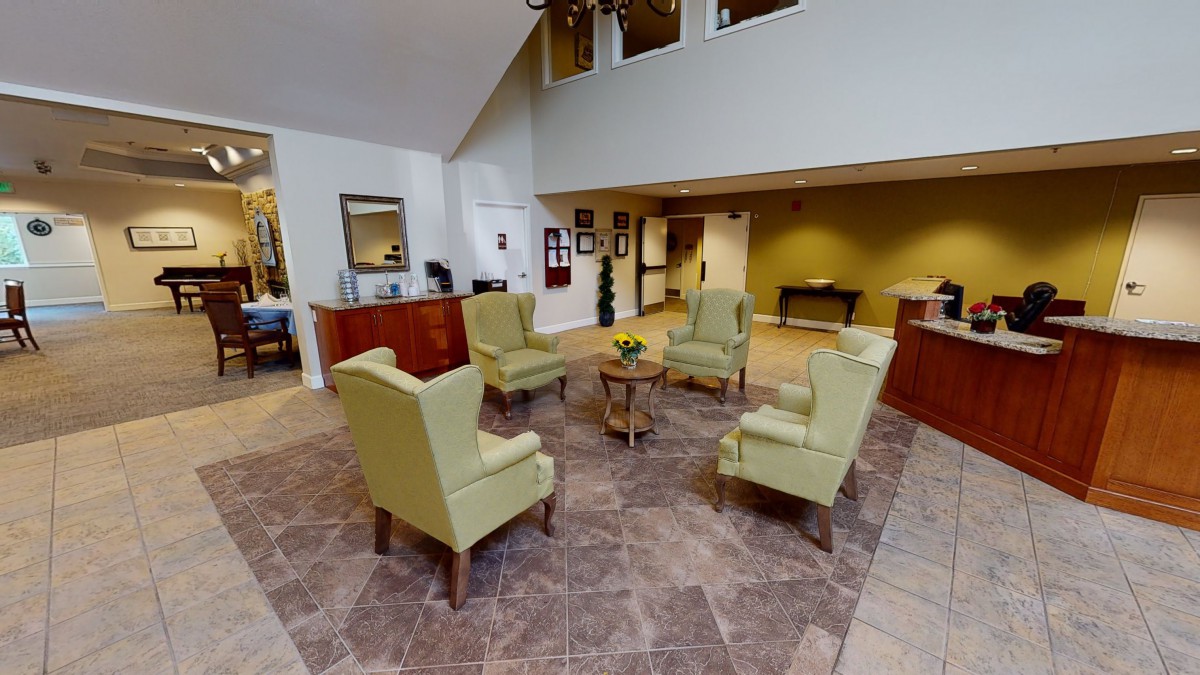 A modern, spacious lobby with a central seating area featuring four chairs arranged around a small table.