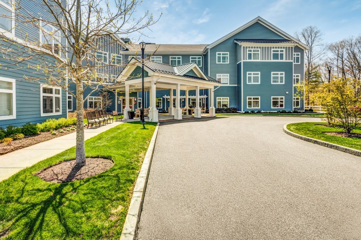 A modern residential building with a driveway and well-maintained landscaping on a sunny day.