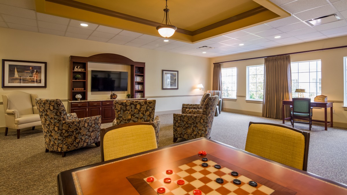 A cozy living room with comfortable seating, a television, and a game table for playing checkers.