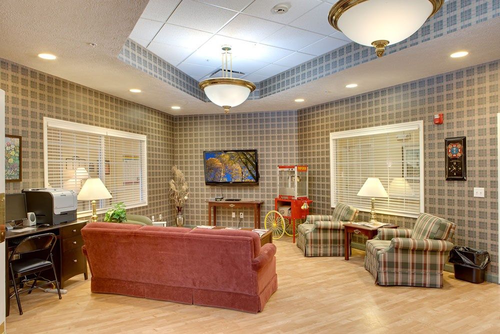 A cozy living room with plaid wallpaper, featuring comfortable seating, a television, and a popcorn machine.
