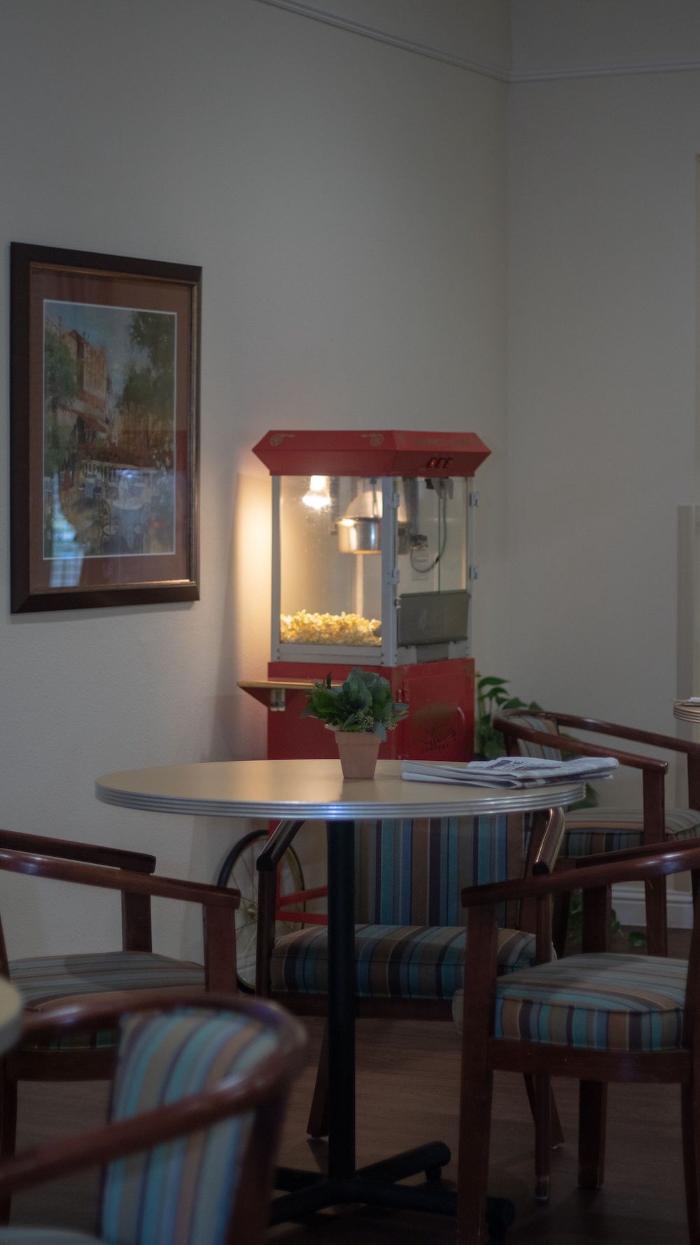 A cozy waiting area featuring a popcorn machine, table with chairs, and decor.