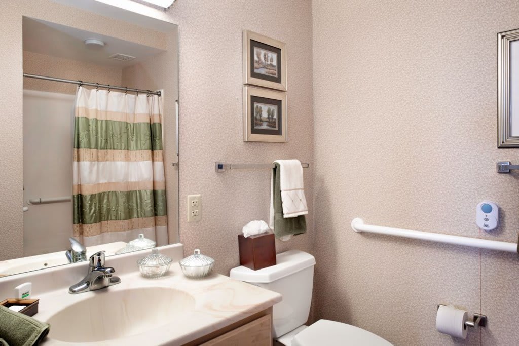 A neatly organized bathroom featuring a sink, toilet, and striped shower curtain.