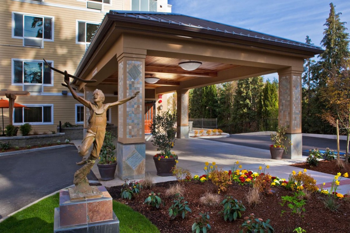 A hotel entrance featuring a decorative statue and well-maintained landscaping.