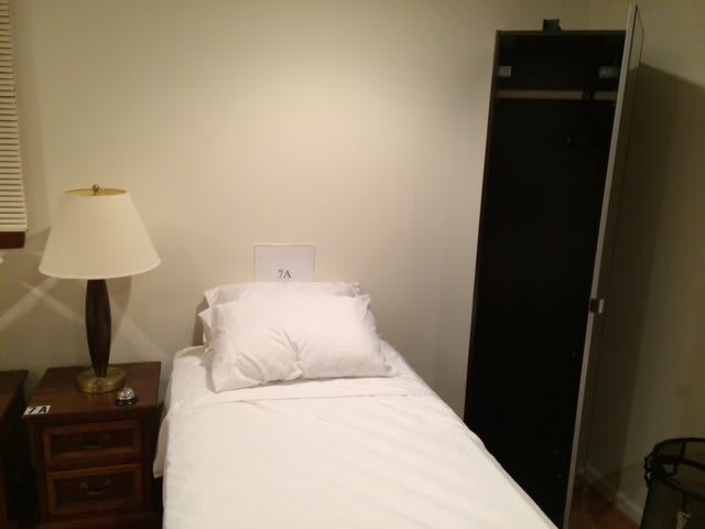 A minimalist bedroom with a single bed, nightstand, and wardrobe.