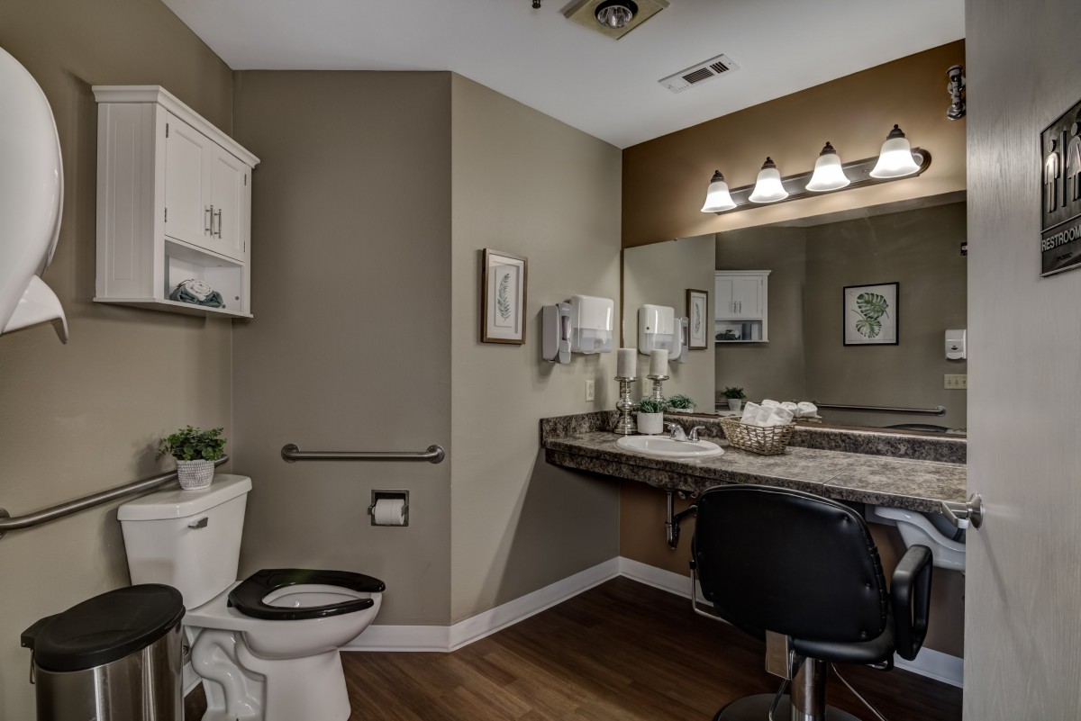 A modern bathroom with a large mirror, vanity lights, and elegant decor.