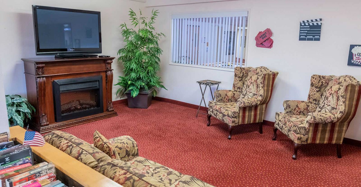 A cozy living room with floral patterned furniture, a television, and a large potted plant.