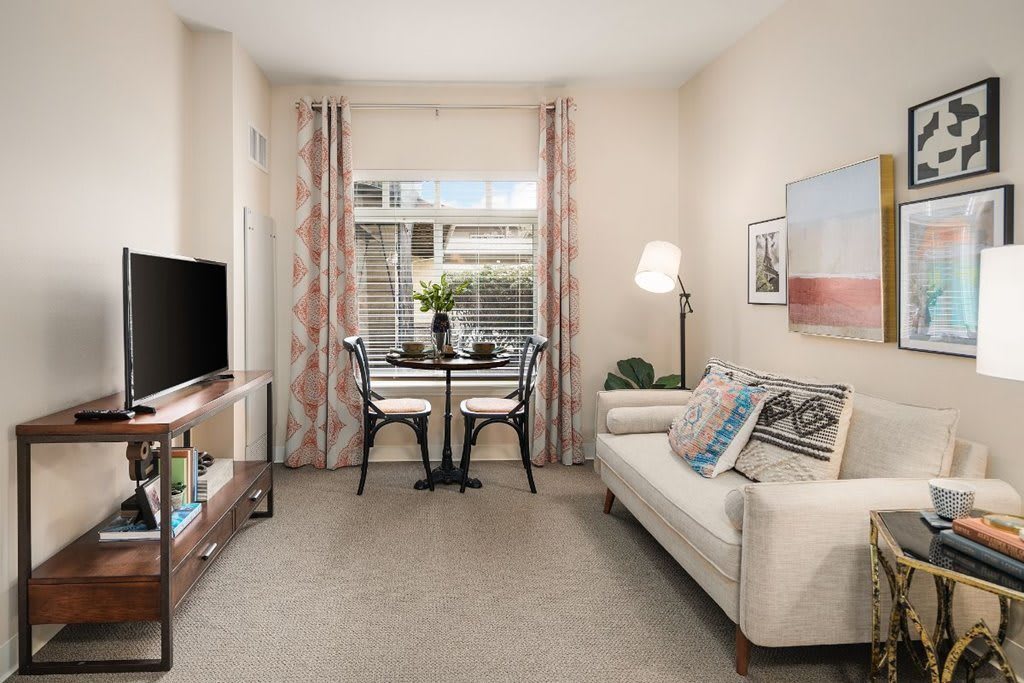 A cozy living room with a sofa, small dining area, and a TV.