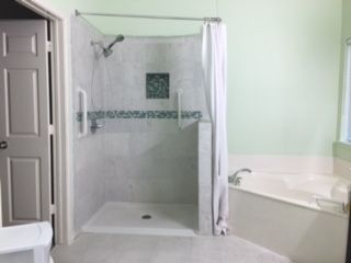 A bathroom with a tiled shower and a curtain next to a bathtub.
