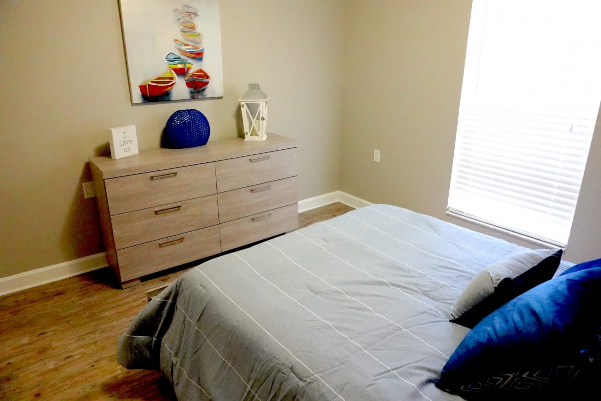 A neatly arranged bedroom with a bed and a wooden dresser.