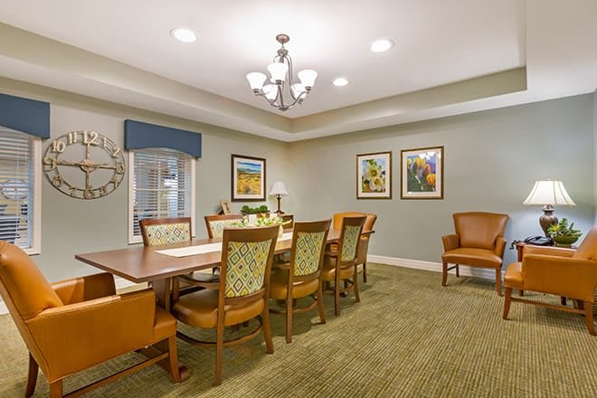 A well-lit dining room with a large table, chairs, and decorative artwork on the walls.