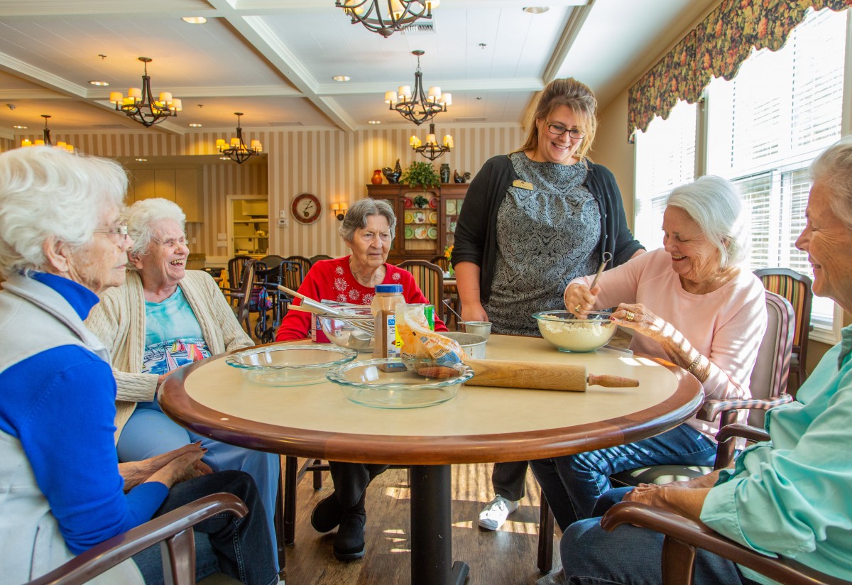 A group of elderly people enjoying a baking activity together inside a cozy community room.