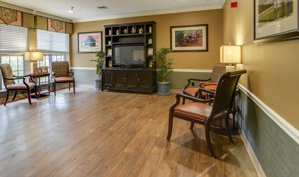 A cozy living room with a television, wooden flooring, and comfortable seating.