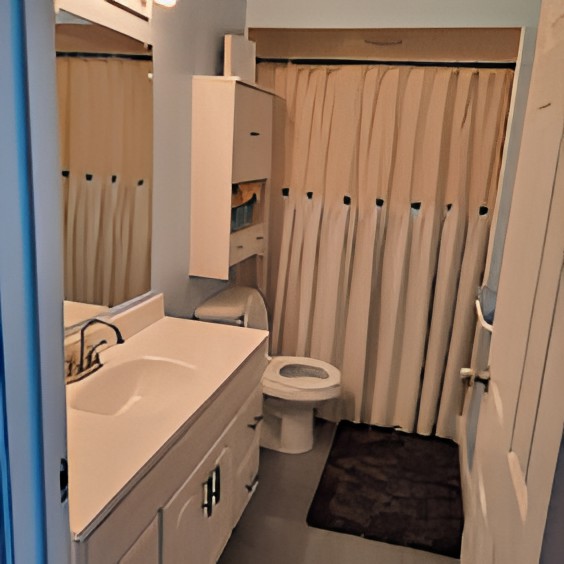 A compact bathroom with a sink, toilet, and shower area.