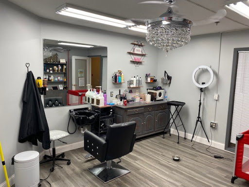 A modern hair salon featuring a stylish barber chair, elegant chandelier, and organized styling products.