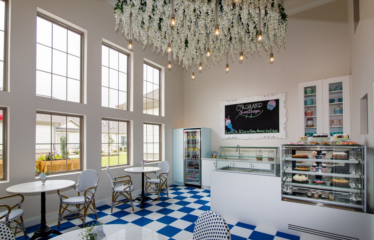 A modern cafe interior with checkered flooring, large windows, and elegant hanging lights.