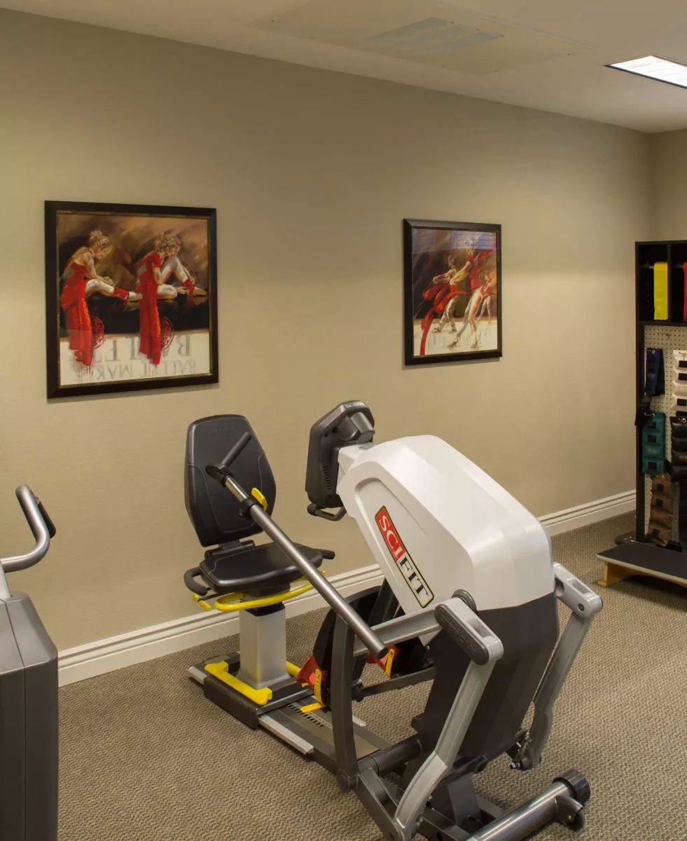 A gym room with exercise machines and framed posters on the wall.