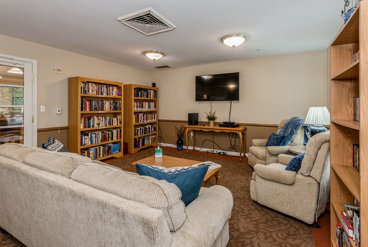 A cozy living room with sofas and bookshelves, featuring a wall-mounted television.