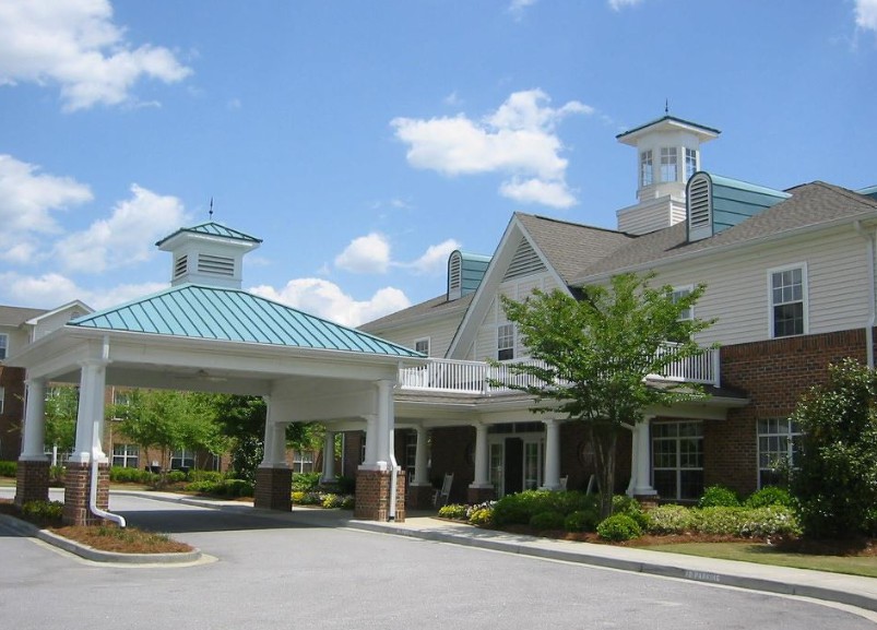 A building with a covered entrance and blue rooftops surrounded by greenery.