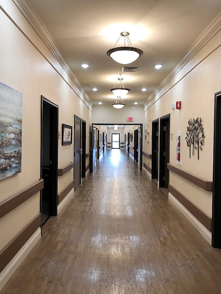 A well-lit hallway with multiple doors and artwork on the walls.