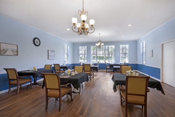 A spacious dining room with elegant furnishings and a chandelier.