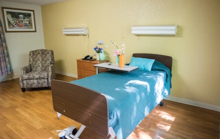 A clean and organized hospital room with a single bed and medical equipment.