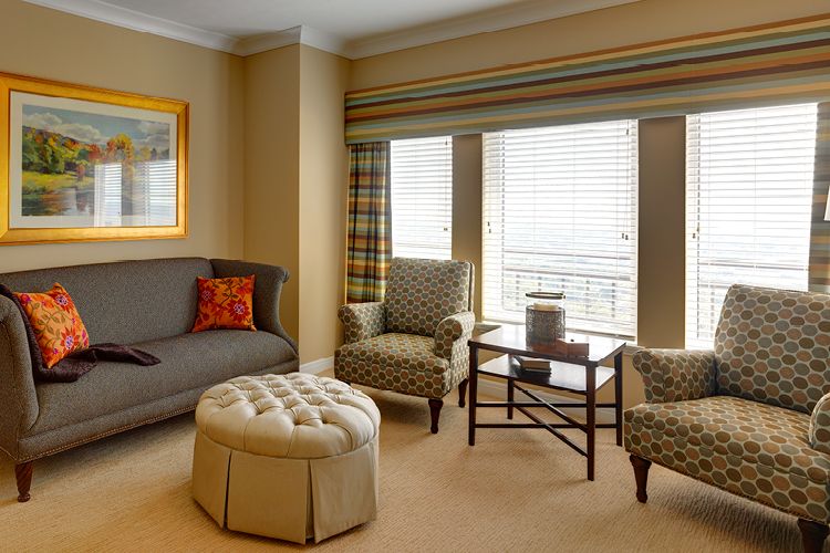 A cozy living room with a sofa, armchairs, and a coffee table near large windows.