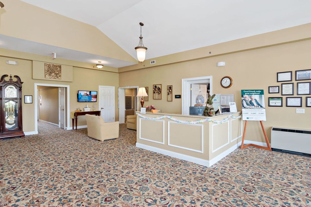 The image shows a reception area with a desk and seating in a carpeted lobby.