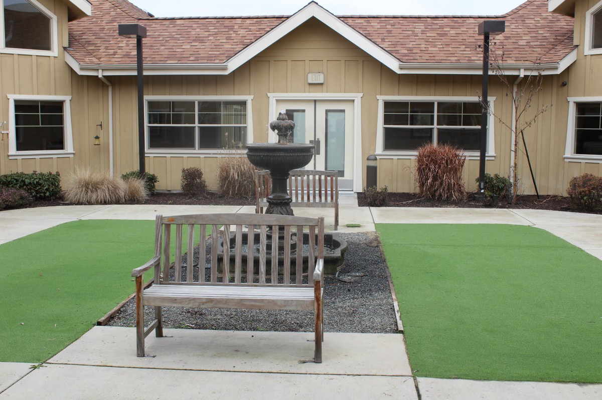 A courtyard with benches and a central fountain in front of a building.