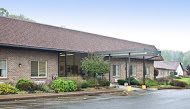 A brick building with a glass entrance and surrounding landscaping.