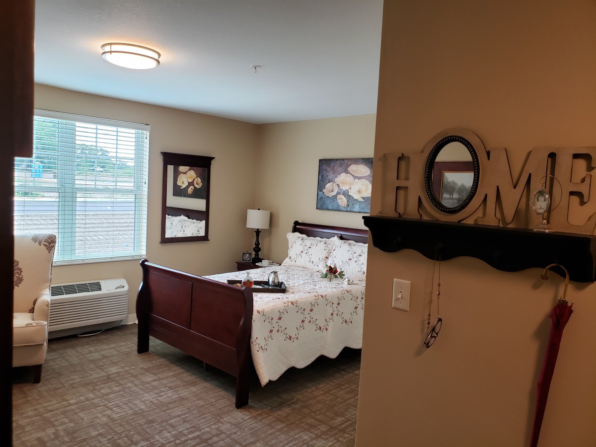 A cozy bedroom with a neatly made bed, wall art, and decorative elements.