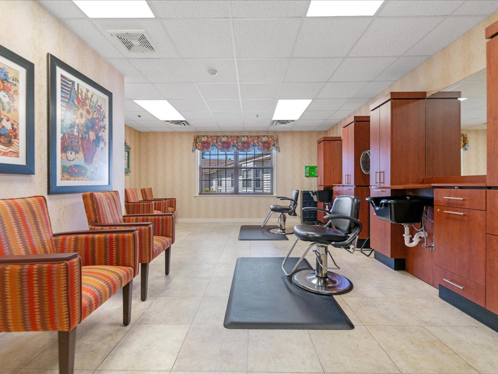A tidy hair salon featuring a waiting area with striped chairs and two stylist stations.