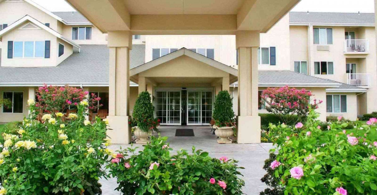 A welcoming entrance to a building surrounded by lush landscaping and colorful flowers.
