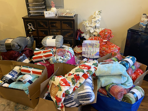 A cluttered room filled with boxes and various items, including clothes and blankets.