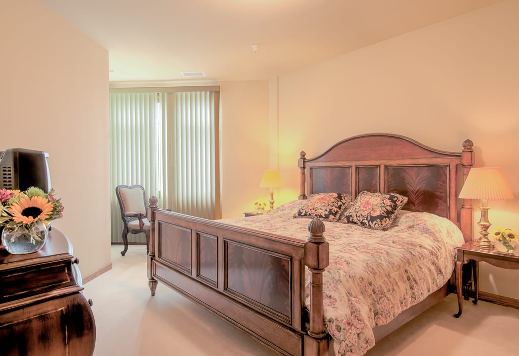 A cozy bedroom featuring a wooden bed, floral bedding, and soft lighting.