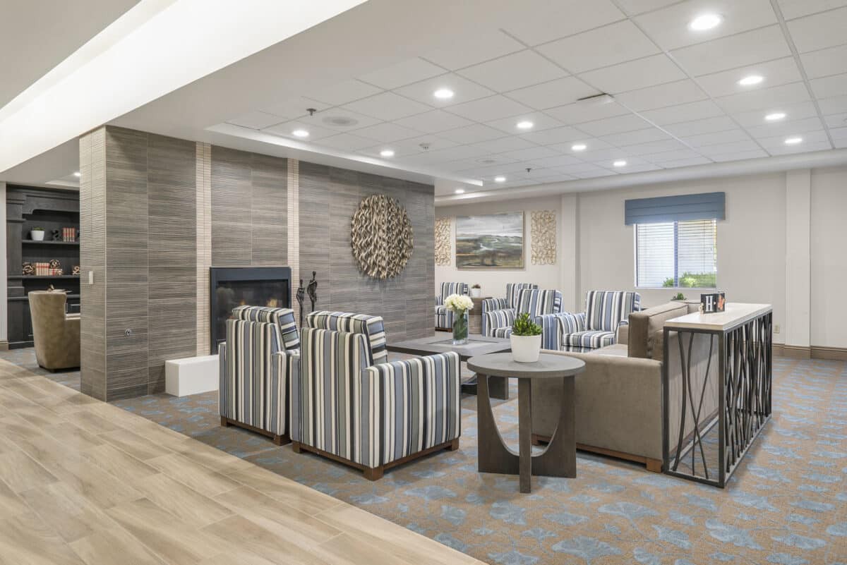 A modern living room with striped chairs and a fireplace, featuring elegant decor.