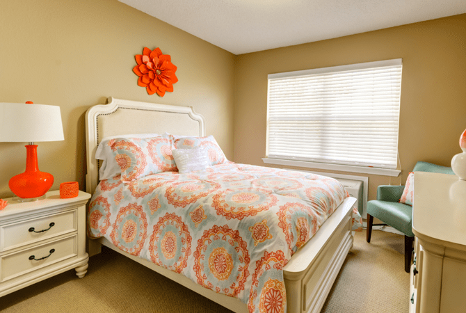 A cozy bedroom with colorful bedding and a stylish wall decoration.