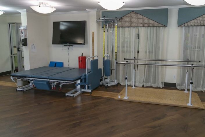 A physical therapy room equipped with rehabilitation equipment and exercise bars.