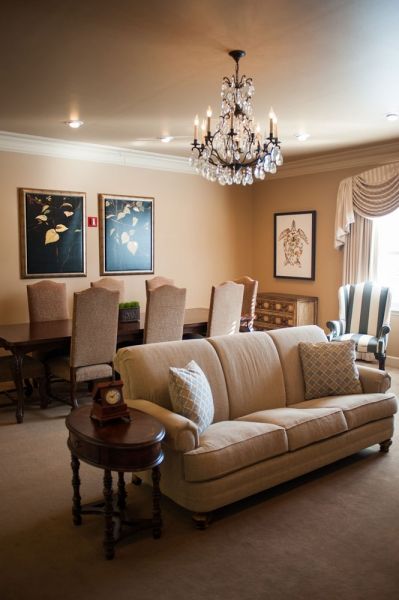 An elegant living room with a chandelier, sofa, and dining area.