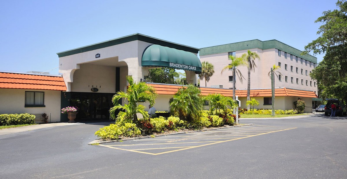 A hotel entrance with palm trees and well-maintained landscaping.
