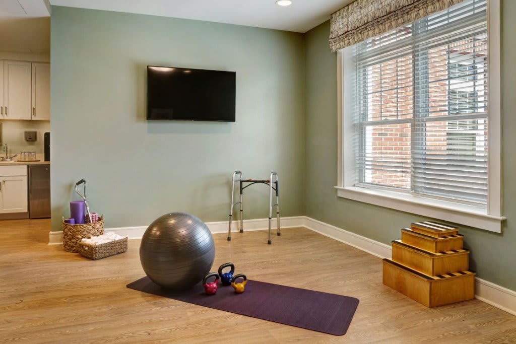 A home exercise room with equipment including a yoga mat, exercise ball, and kettlebells.