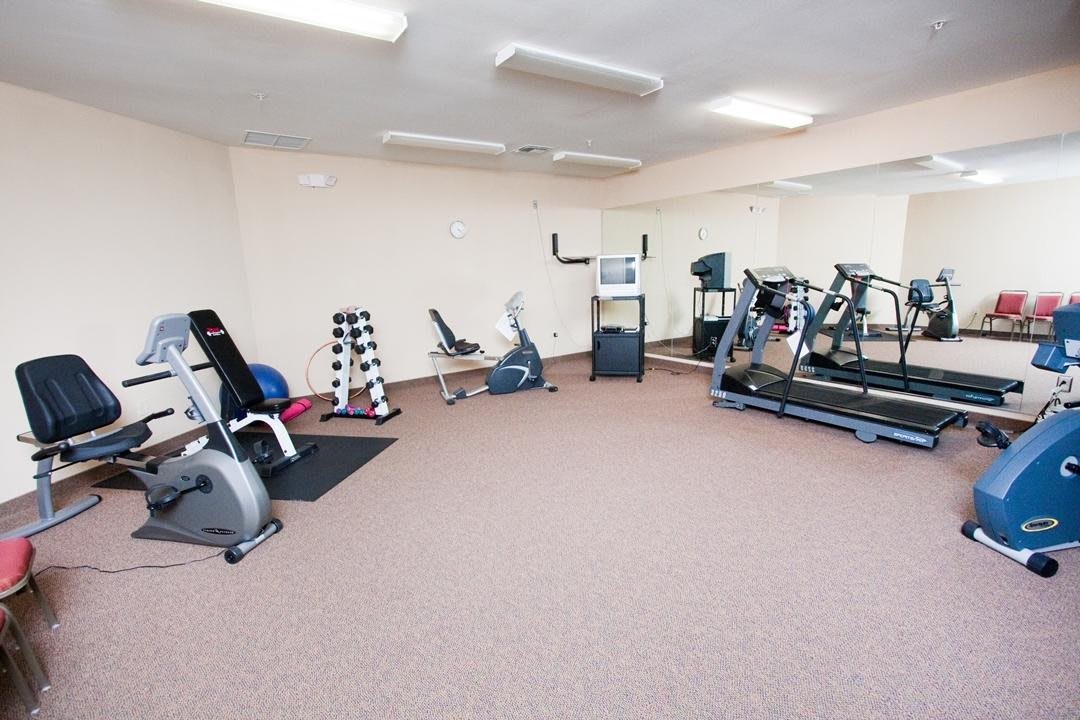 A small gym with various exercise equipment including treadmills and dumbbells.