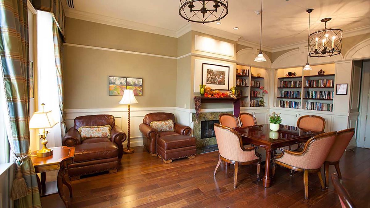 A cozy living room featuring leather armchairs, a wooden table, and a fireplace.