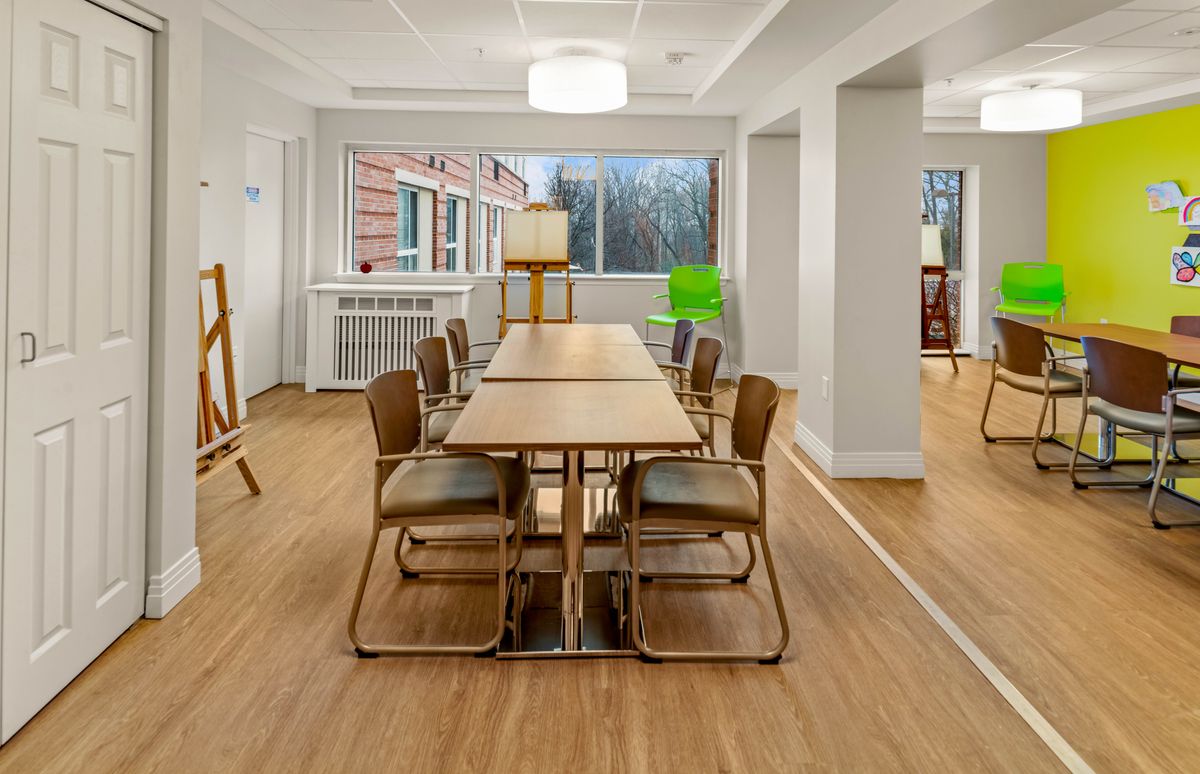 A modern dining room with a wooden table and chairs, featuring minimalist design elements and ample natural light.